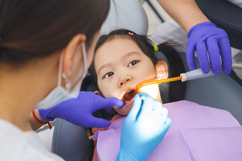 Little Girl at Dental Check-Up, male dentist checking and cleaning teeth