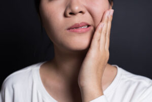 woman holding jaw in pain